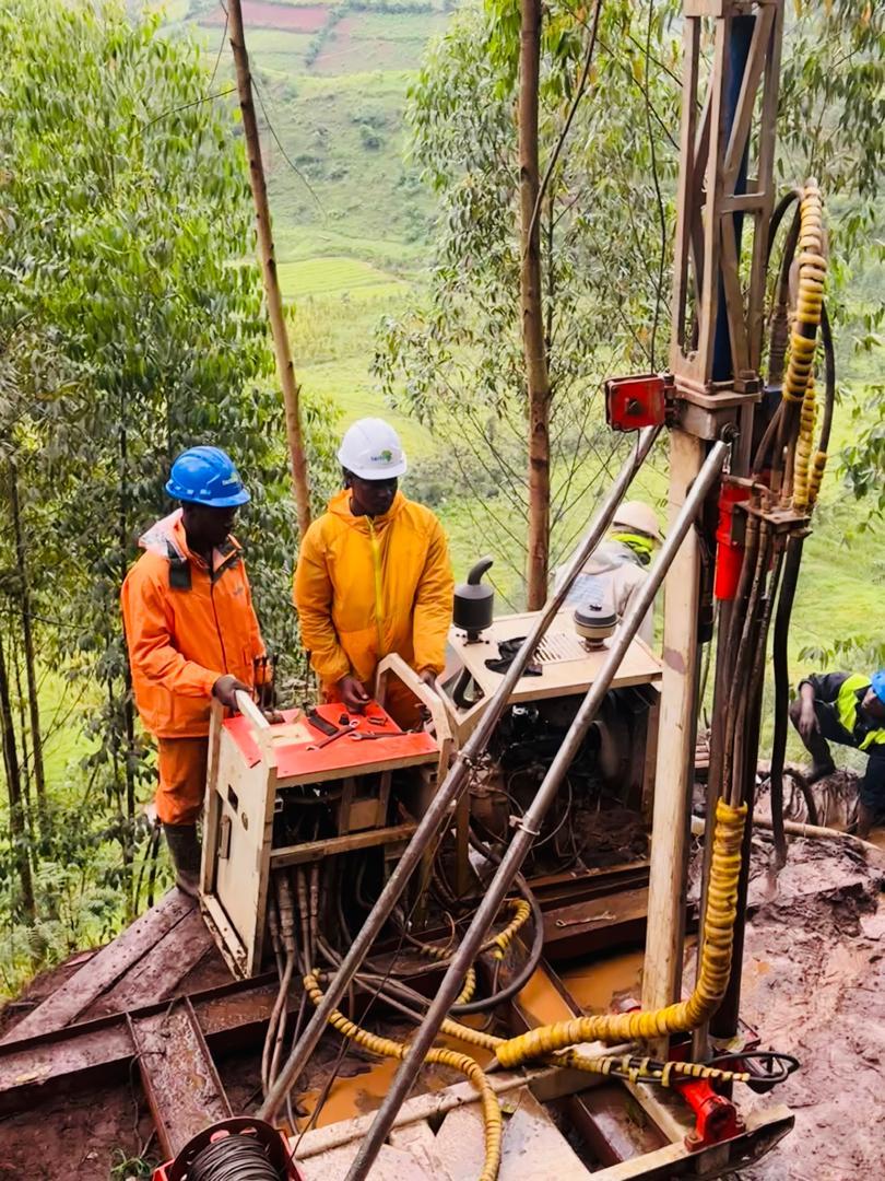 Two Tectoni crew operating drill-rig controls on a terraced highland slope