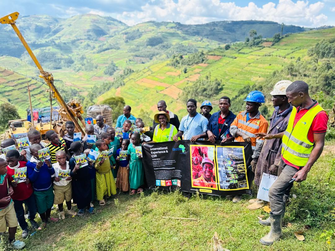 Tectoni staff and local community with children and a banner, terraced mountains behind