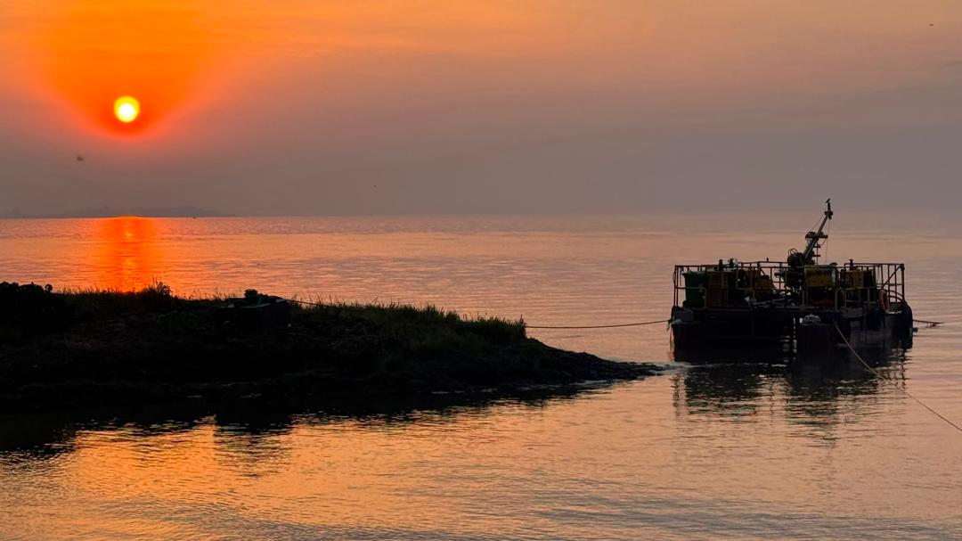 Marine drilling barge silhouetted against a red sunset over the lake