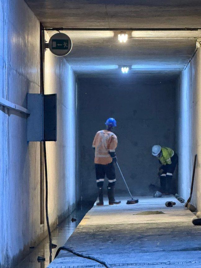 Crew inside a dam gallery during relief drain cleaning